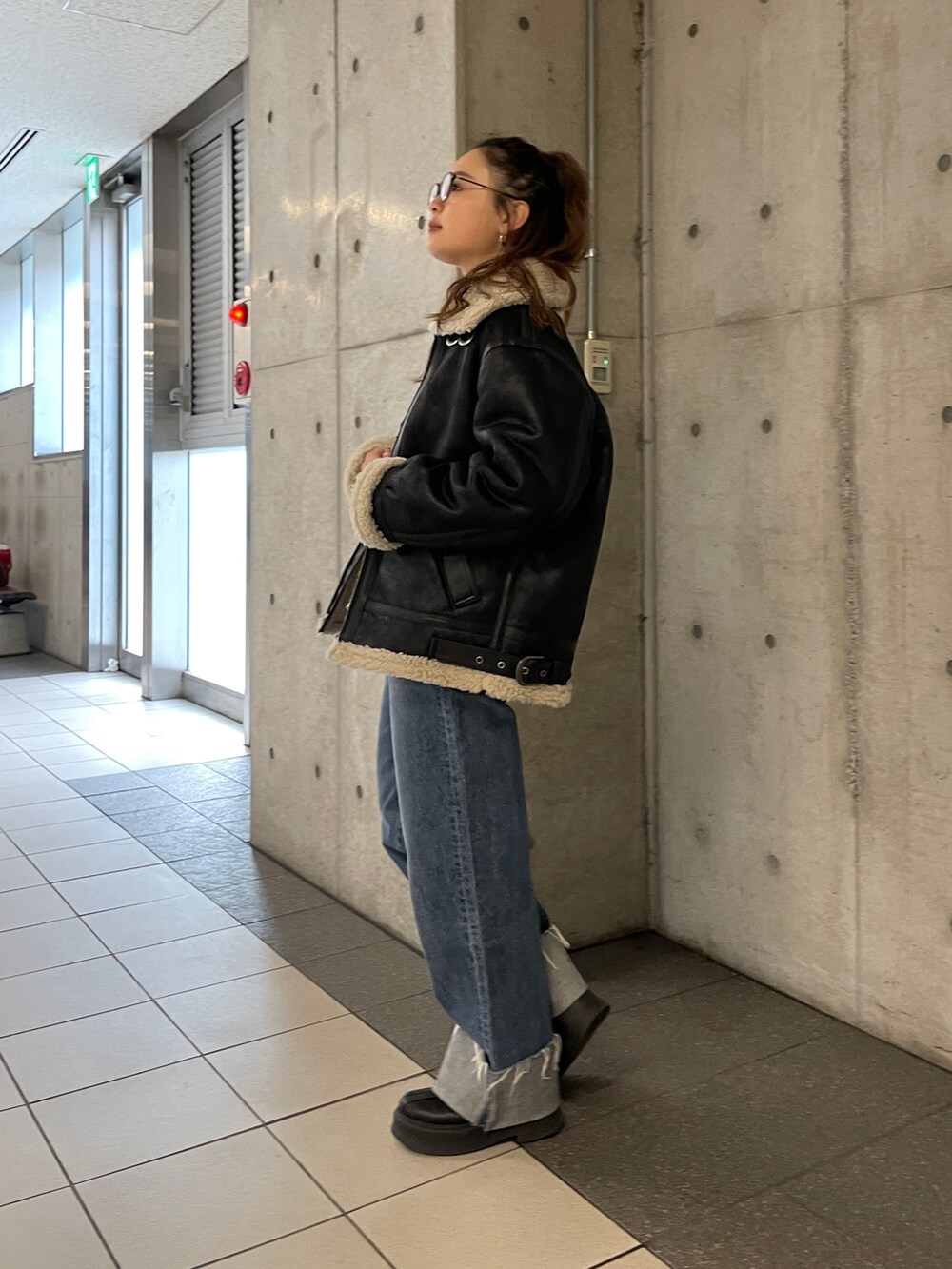 ブラック系のムートンコート、ブルー系のデニムパンツ、グレー系のニット/セーターを着用したレディースの冬コーディネートの9枚目の写真