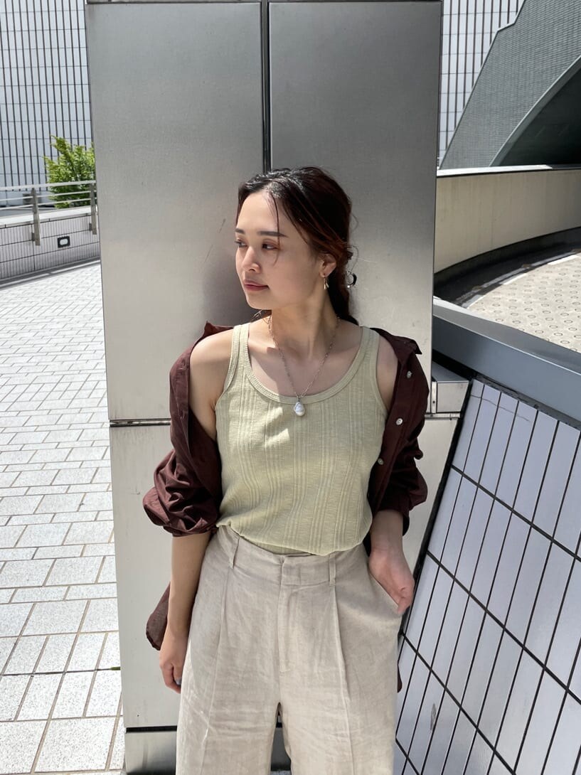 グリーン系のタンクトップ、ブラック系のサンダル、ホワイト系のその他パンツを着用したレディースの夏コーディネートの5枚目の写真