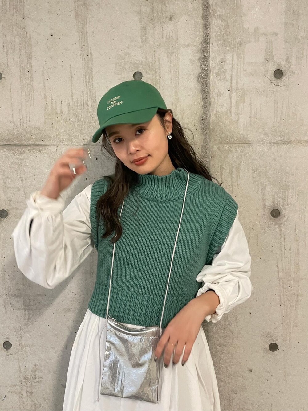 シルバー系のショルダーバッグ、グリーン系のワンピース、グリーン系のキャップを着用したレディースの冬コーディネートの5枚目の写真