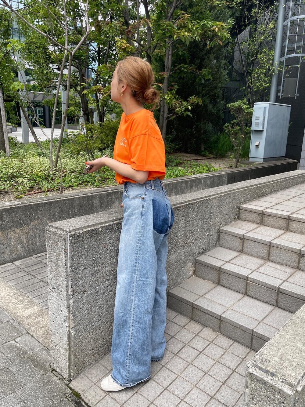 オレンジ系のTシャツ/カットソー、ブルー系のデニムパンツ、ホワイト系のスニーカーを着用したレディースの夏コーディネートの5枚目の写真