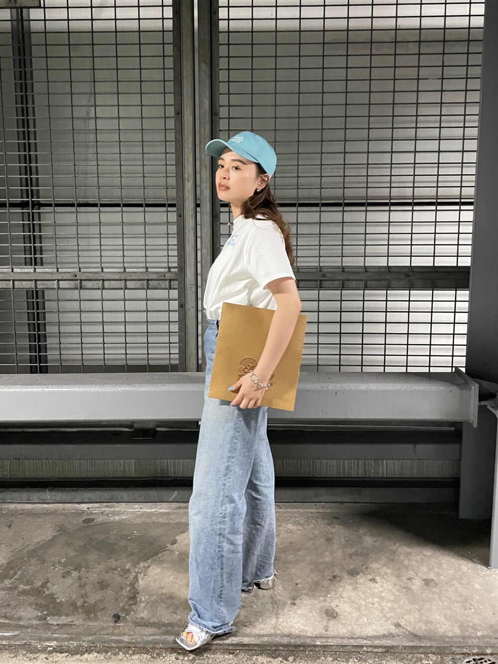 ブルー系のデニムパンツ、シルバー系のサンダル、ブルー系のキャップを着用したレディースの春コーディネートの3枚目の写真