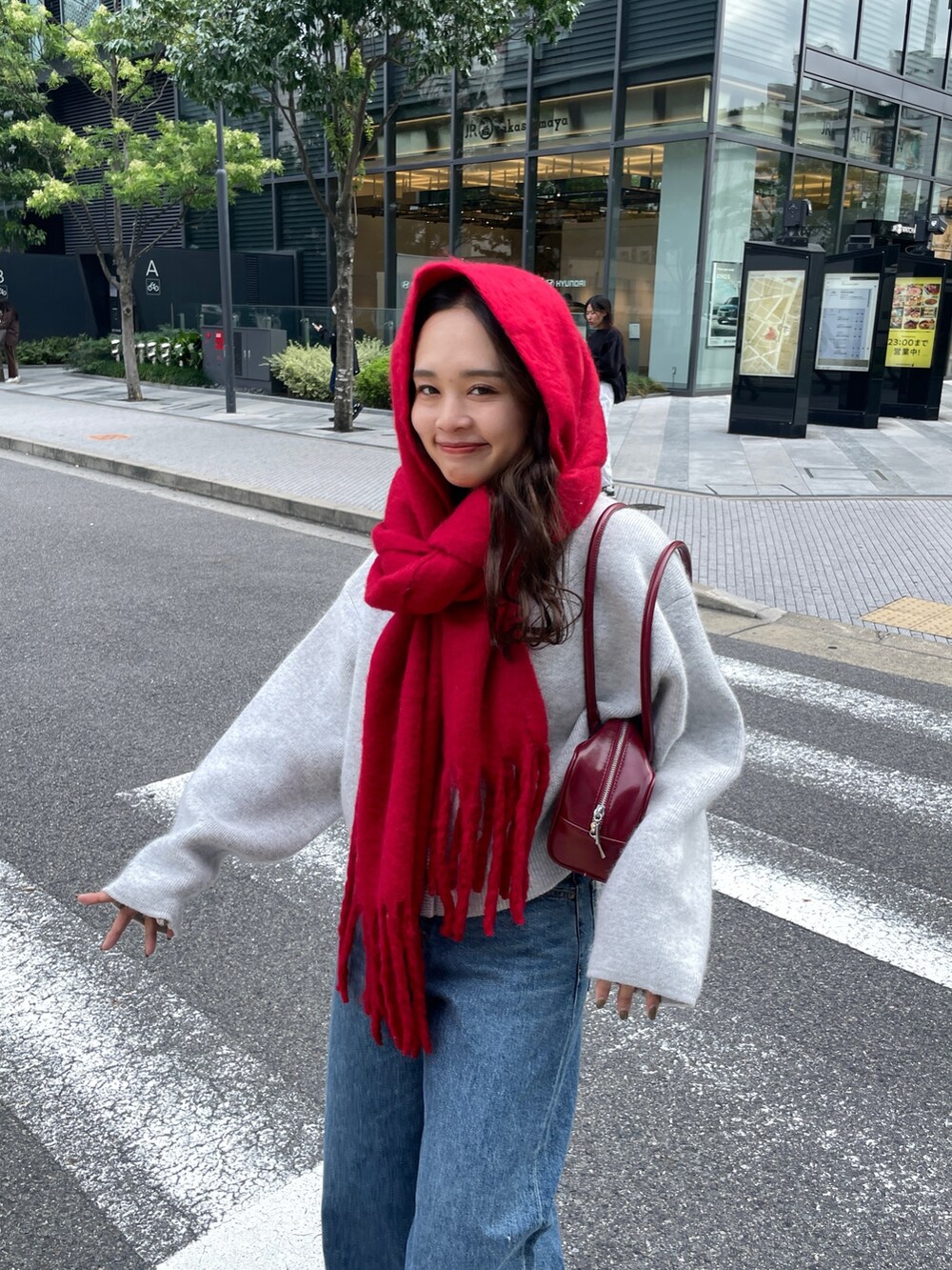 ブルー系のデニムパンツ、レッド系のハンドバッグ、グレー系のカーディガン/ボレロを着用したレディースの秋コーディネートの4枚目の写真