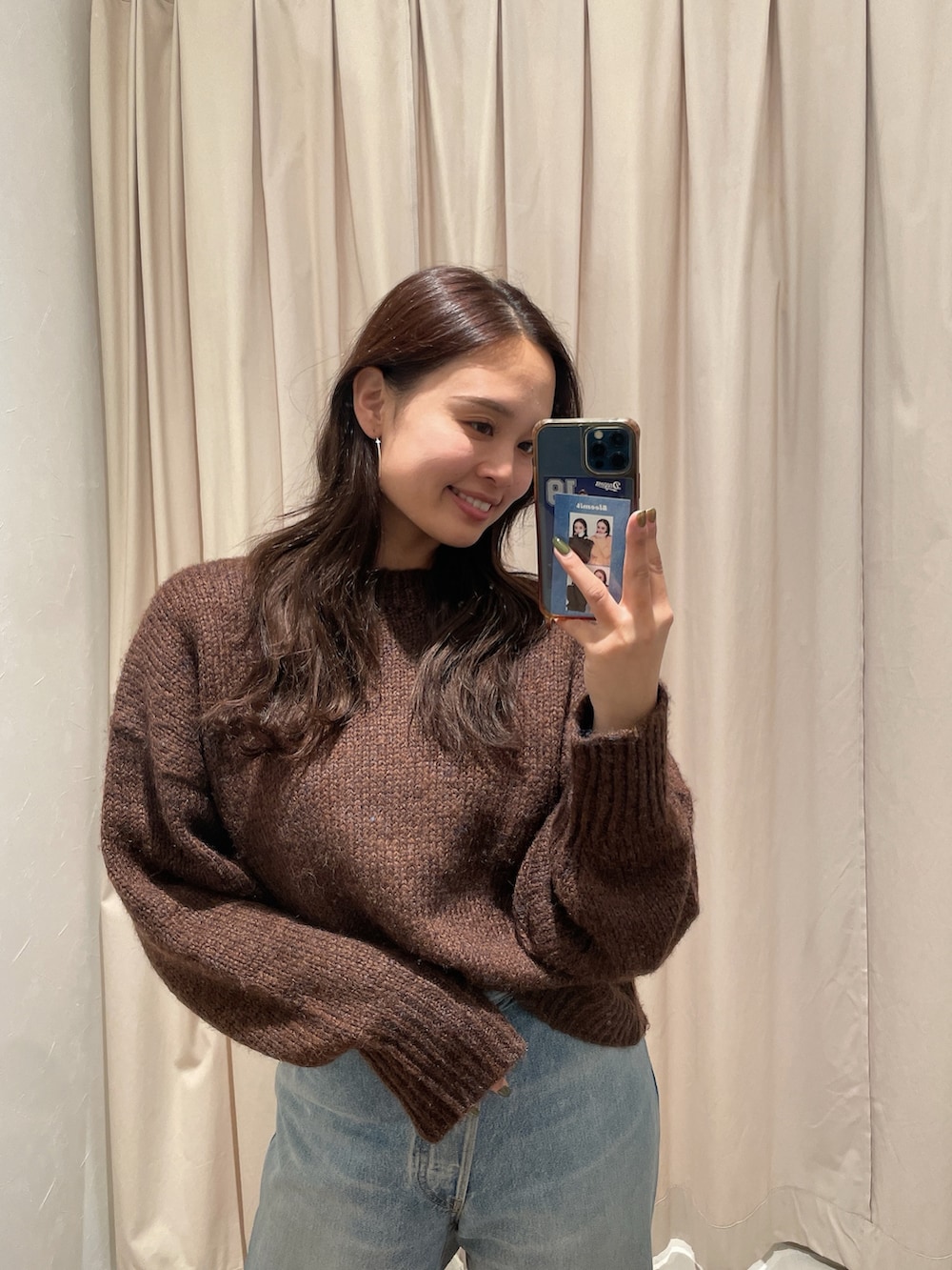 ブラウン系のニット/セーター、ブルー系のデニムパンツを着用したレディースの秋コーディネートの2枚目の写真