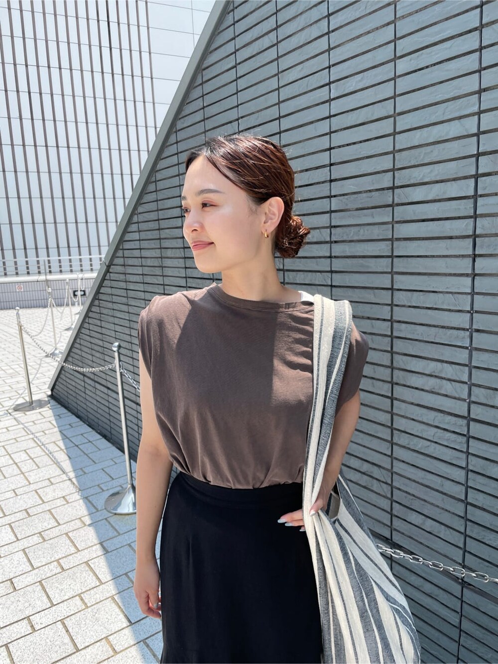 ホワイト系のサンダル、ブラウン系のタンクトップ、ブラック系のスカートを着用したレディースの夏コーディネートの3枚目の写真