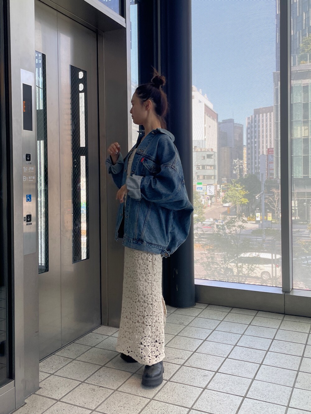 ブルー系のデニムジャケット、ベージュ系のワンピースを着用したレディースの春コーディネートの4枚目の写真