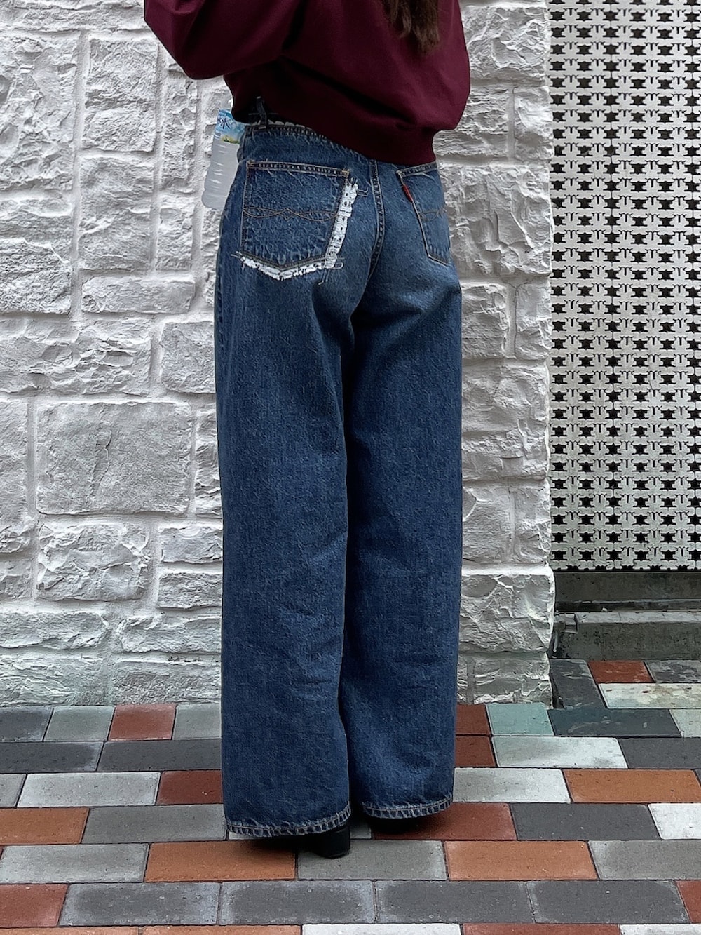 ブルー系のデニムパンツ、レッド系のスウェットを着用したレディースの秋コーディネートの2枚目の写真