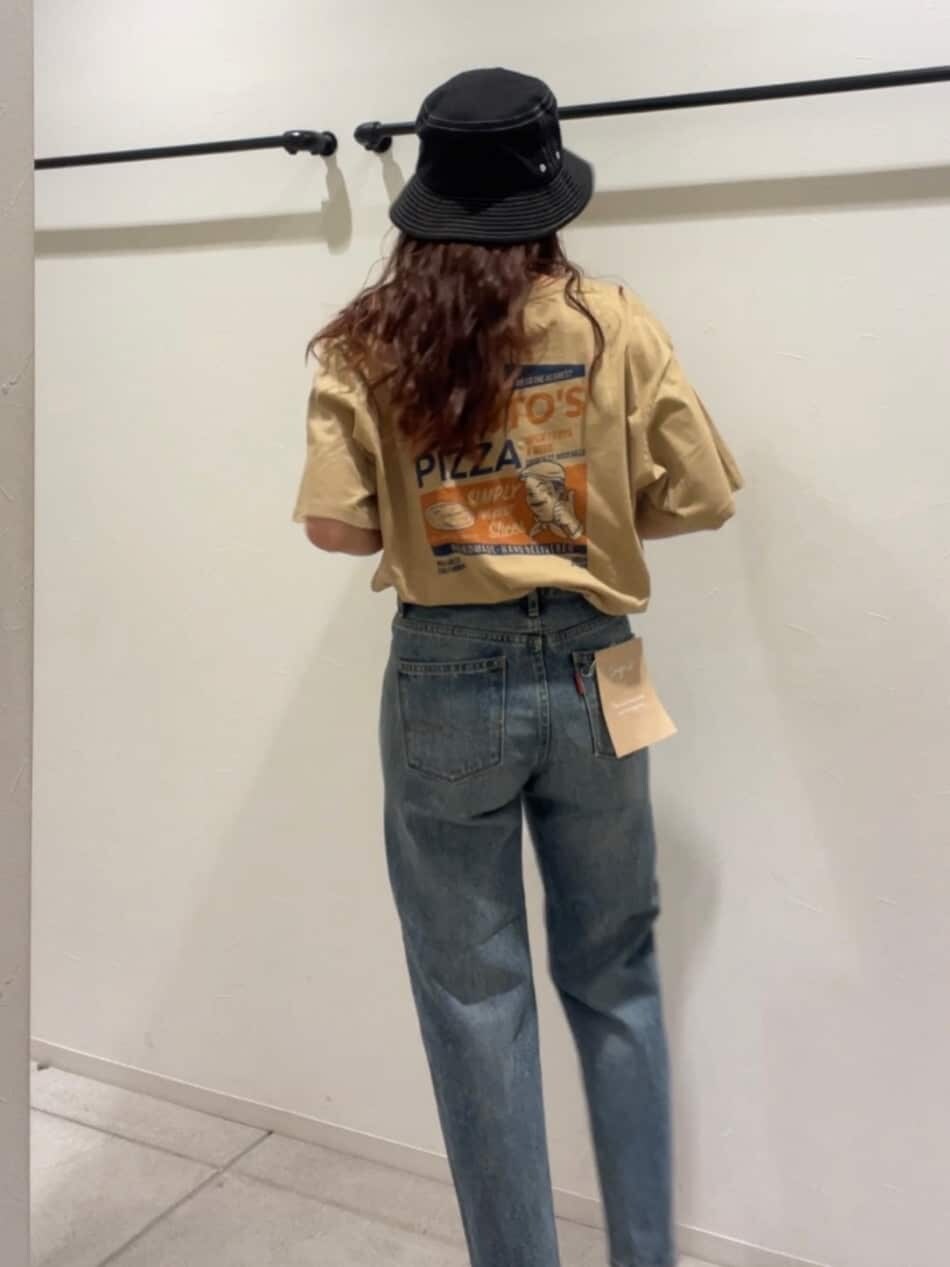 ブルー系のデニムパンツ、ブラック系のサンダル、ベージュ系のTシャツ/カットソーを着用したレディースの夏コーディネートの3枚目の写真