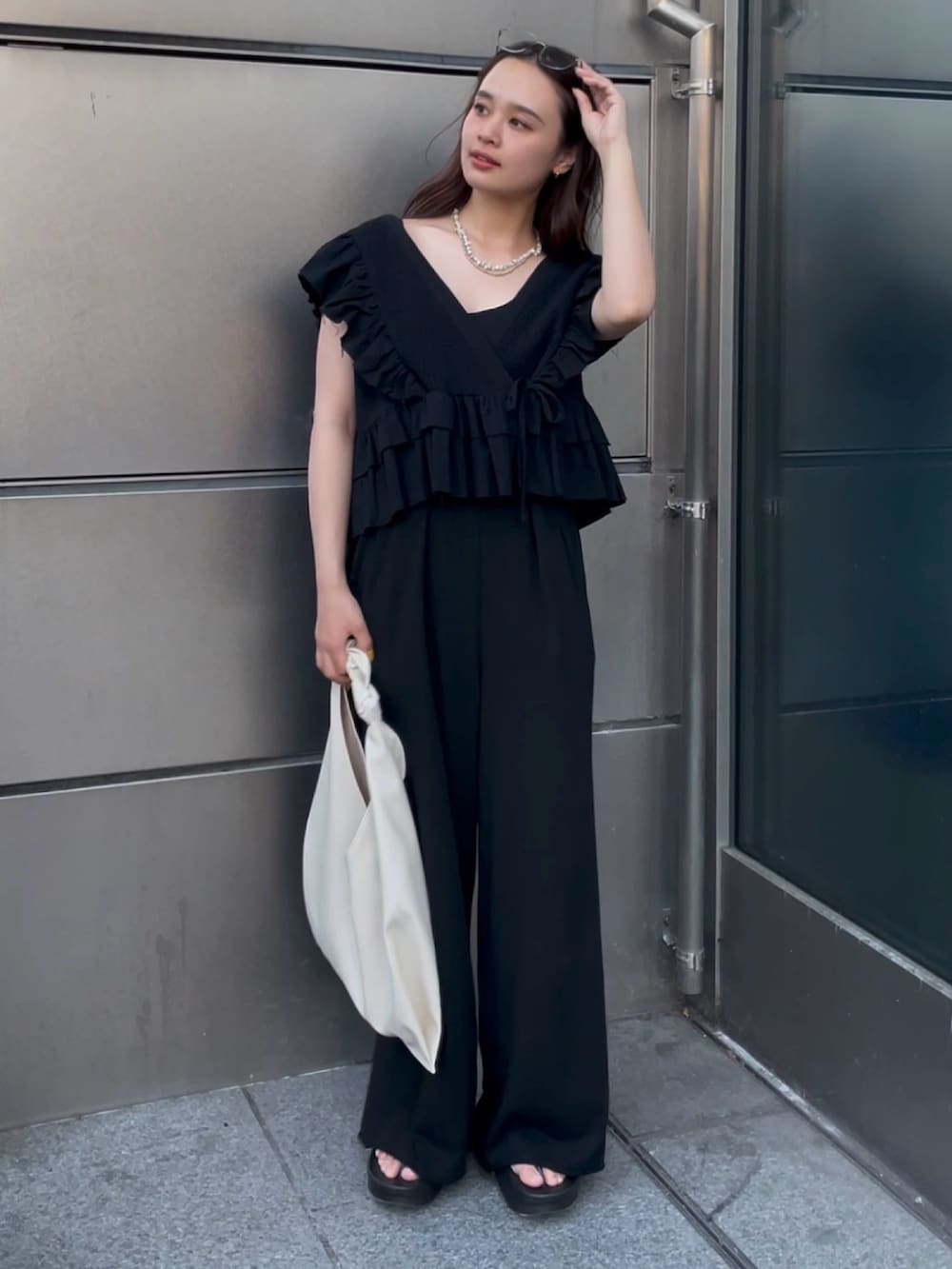 ブラック系のその他パンツ、ブラック系のシャツ/ブラウス、ホワイト系のハンドバッグを着用したレディースの春コーディネートの2枚目の写真