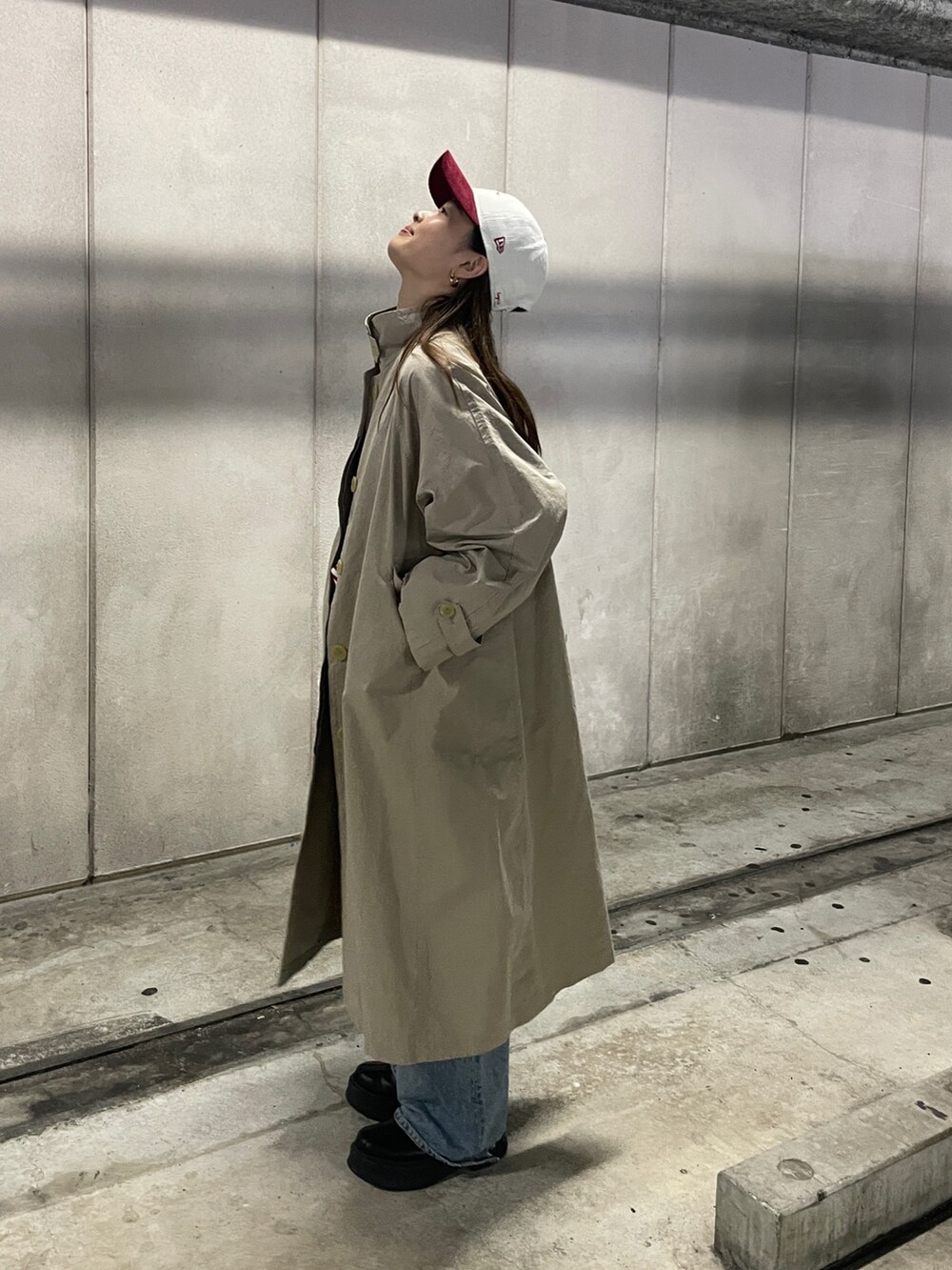 ブルー系のデニムパンツ、ベージュ系のステンカラーコート、レッド系のTシャツ/カットソーを着用したレディースの冬コーディネートの2枚目の写真