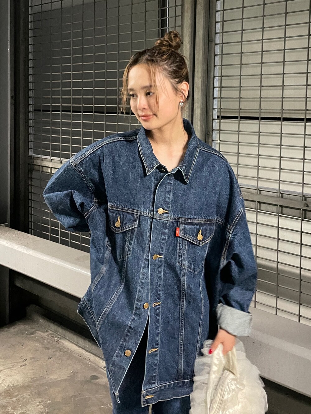 ホワイト系のショルダーバッグ、ブルー系のデニムジャケット、ブルー系のデニムパンツを着用したレディースの夏コーディネートの4枚目の写真