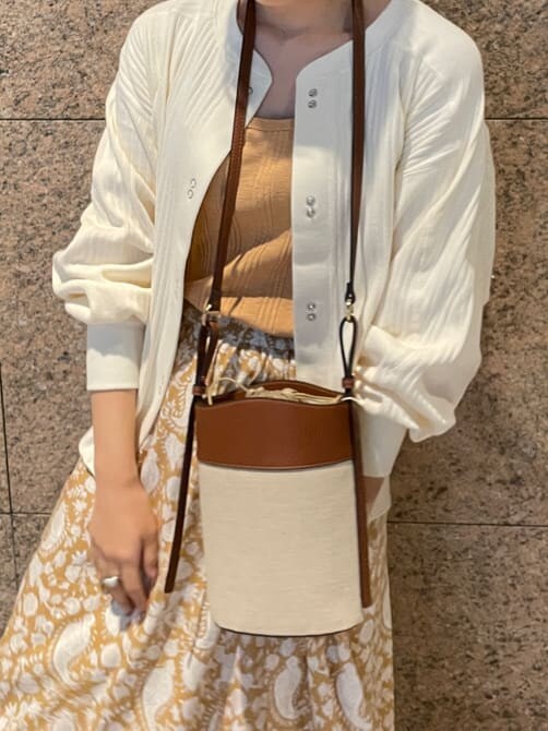 イエロー系のスカート、ホワイト系のパンプス、ホワイト系のカーディガン/ボレロを着用したレディースの冬コーディネートの3枚目の写真