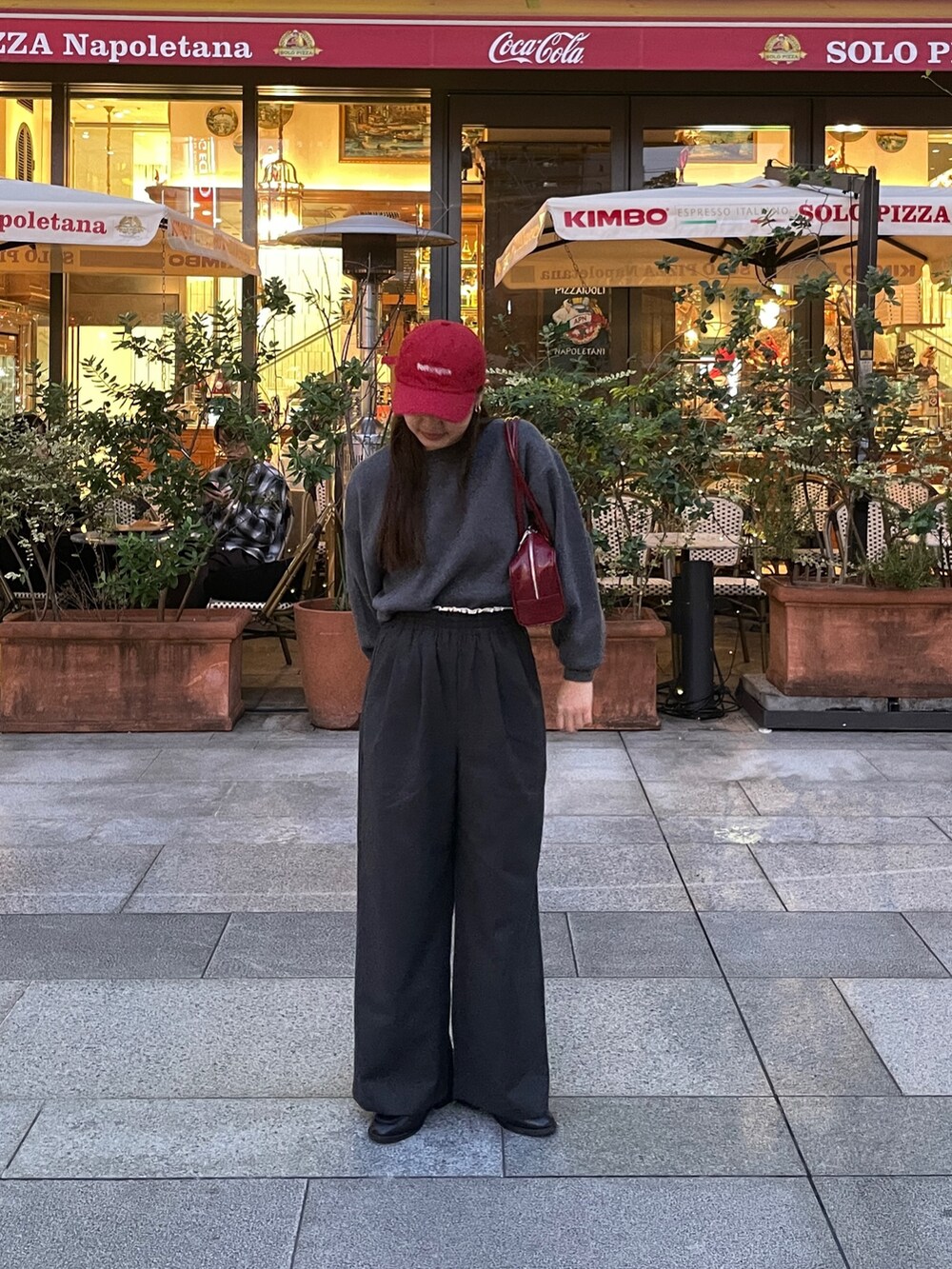 グレー系のその他パンツ、レッド系のハンドバッグ、グレー系のニット/セーターを着用したレディースの秋コーディネートの2枚目の写真