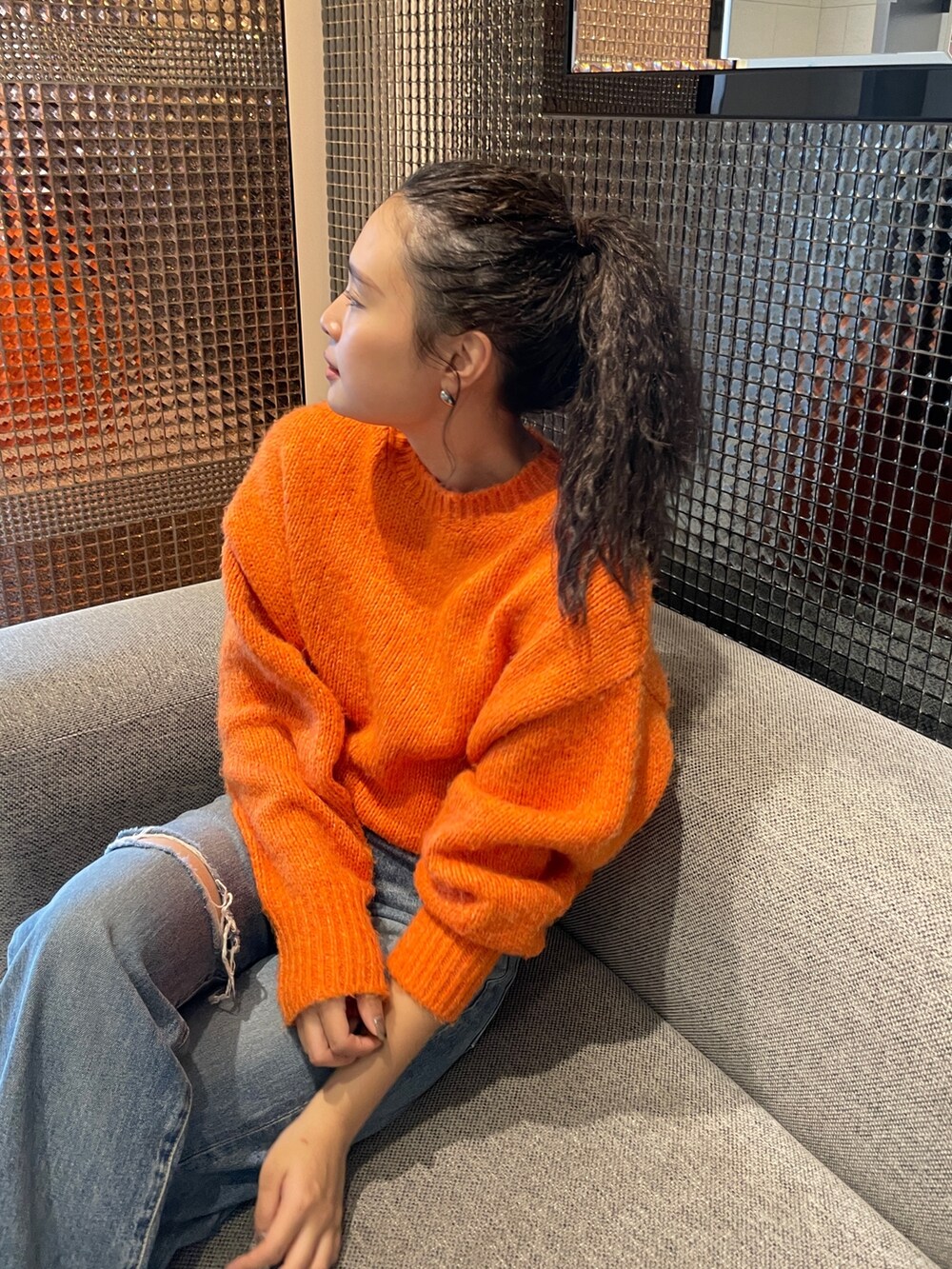 ブルー系のデニムパンツ、ブラック系のブーツ、オレンジ系のニット/セーターを着用したレディースの秋コーディネートの5枚目の写真