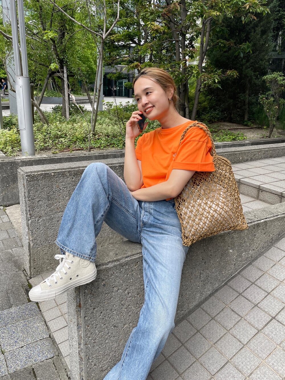 オレンジ系のTシャツ/カットソー、ブルー系のデニムパンツ、ホワイト系のスニーカーを着用したレディースの夏コーディネートの4枚目の写真