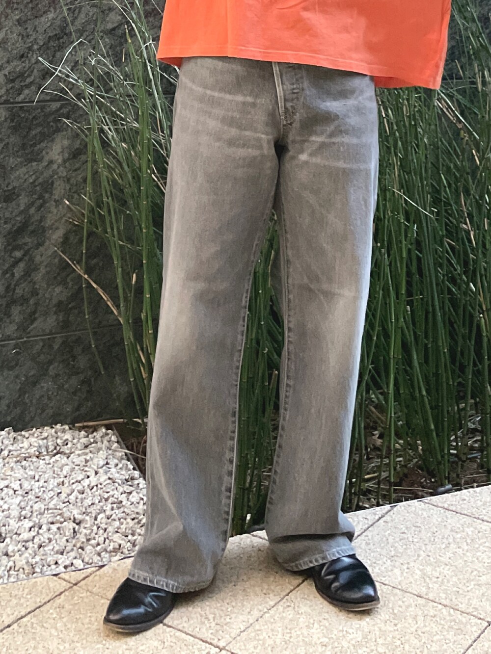 ブラック系のデニムパンツ、オレンジ系のTシャツ/カットソーを着用したレディースの冬コーディネートの3枚目の写真