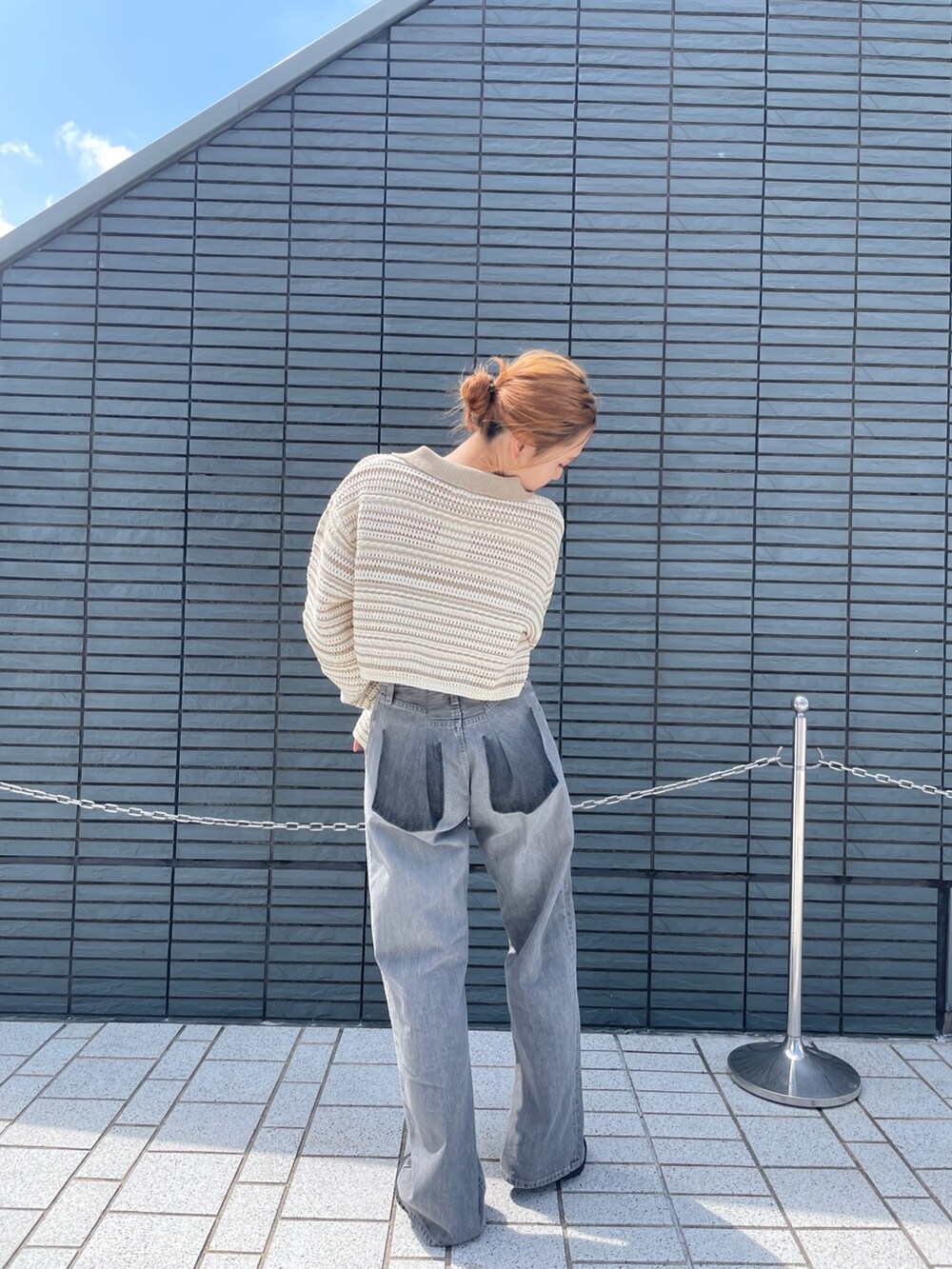 ブラック系のデニムパンツ、ベージュ系のニット/セーターを着用したレディースの春コーディネートの4枚目の写真