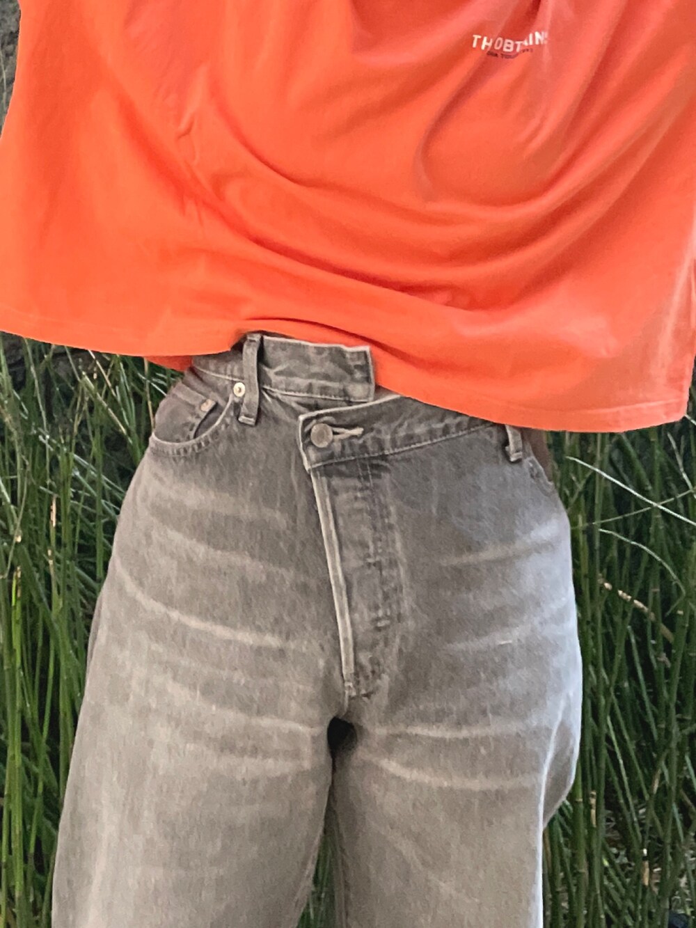 ブラック系のデニムパンツ、オレンジ系のTシャツ/カットソーを着用したレディースの冬コーディネートの4枚目の写真