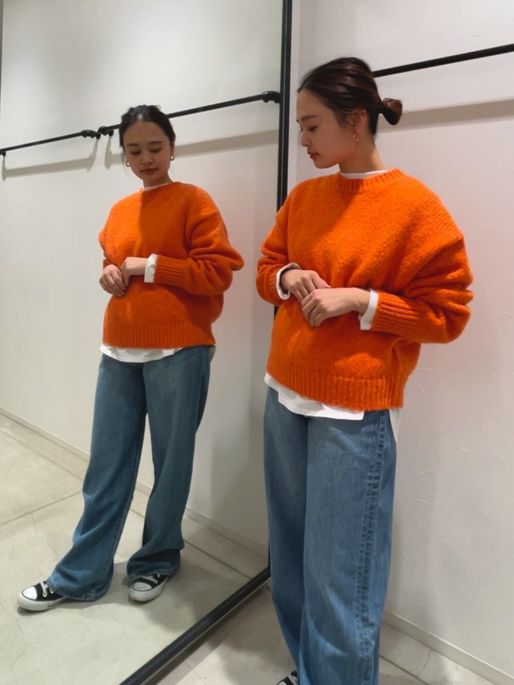 ホワイト系のTシャツ/カットソー、ブルー系のデニムパンツ、オレンジ系のニット/セーターを着用したレディースの冬コーディネートの3枚目の写真