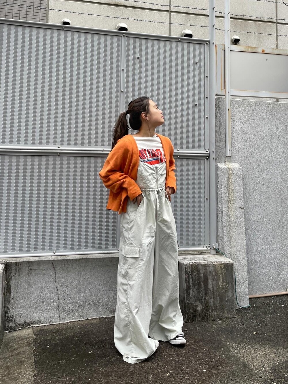 オレンジ系のカーディガン/ボレロ、ホワイト系のTシャツ/カットソー、グレー系のサロペット/オーバーオールを着用したレディースの冬コーディネートの5枚目の写真