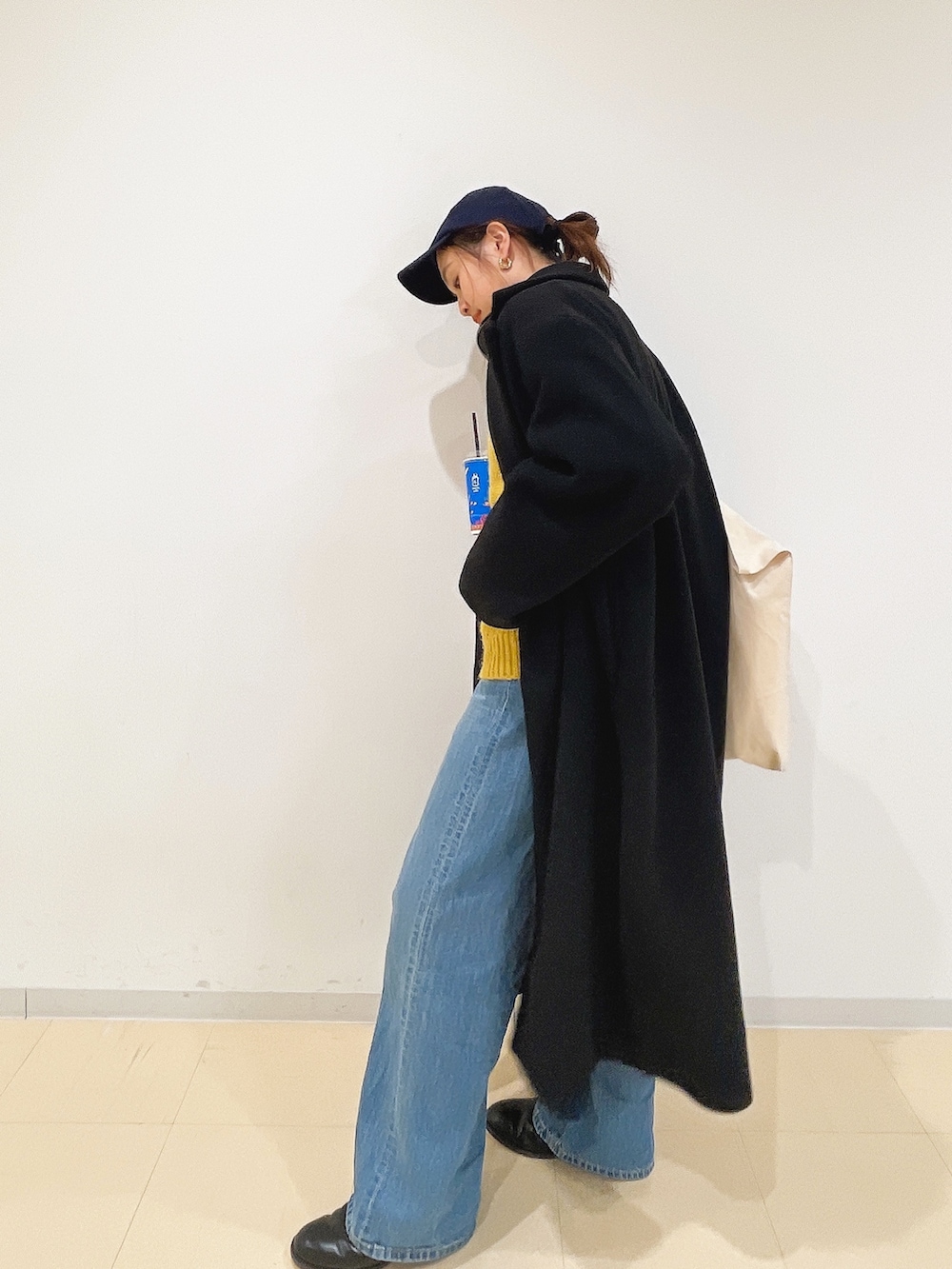 イエロー系のニット/セーター、ホワイト系のハンドバッグ、ブルー系のデニムパンツを着用したレディースの冬コーディネートの6枚目の写真