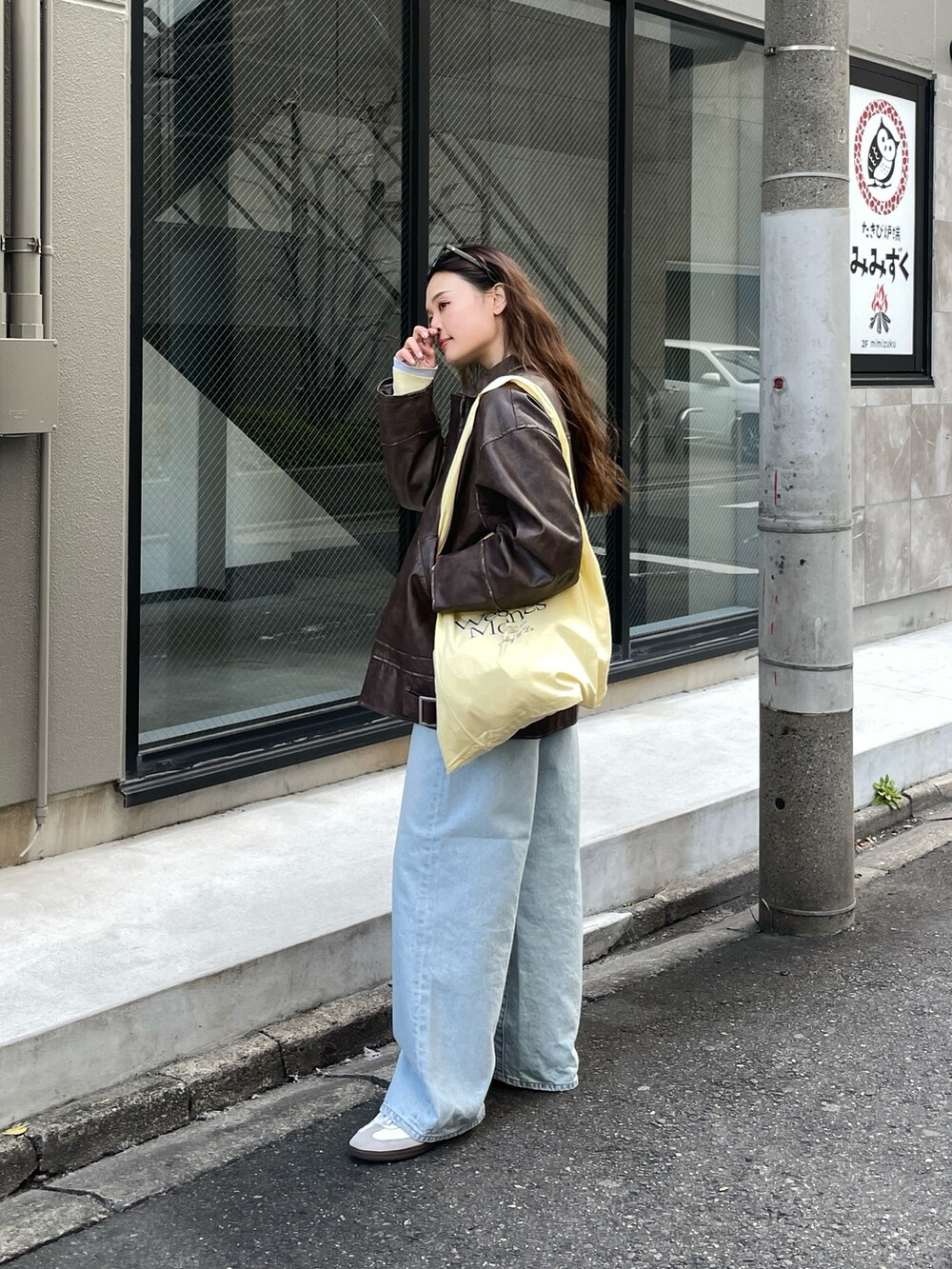 ブラウン系のブルゾン、ブルー系のデニムパンツ、イエロー系のエコバッグ/サブバッグを着用したレディースの冬コーディネートの3枚目の写真