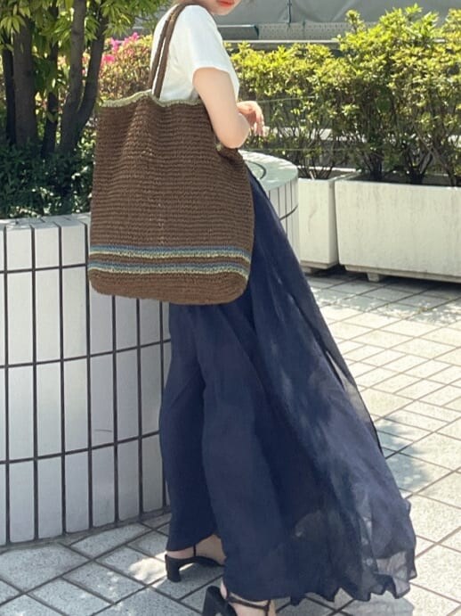ブラウン系のトートバッグ、ホワイト系のTシャツ/カットソー、ブルー系のスカートを着用したレディースの春コーディネートの7枚目の写真