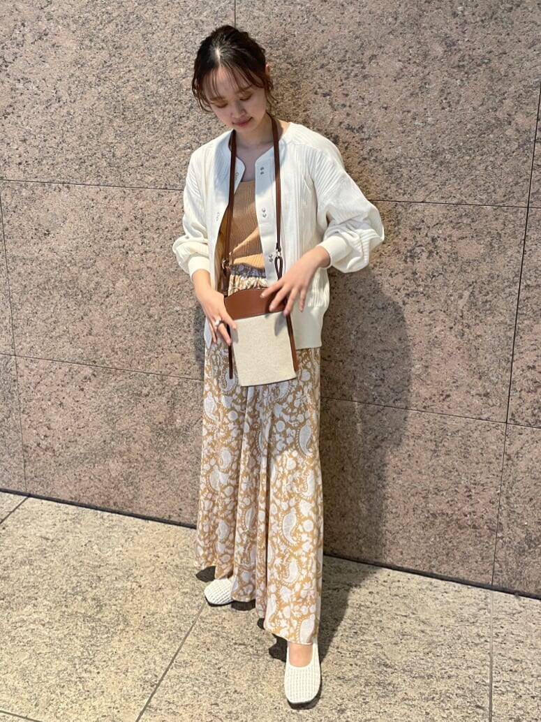 イエロー系のスカート、ホワイト系のパンプス、ホワイト系のカーディガン/ボレロを着用したレディースの冬コーディネートの2枚目の写真