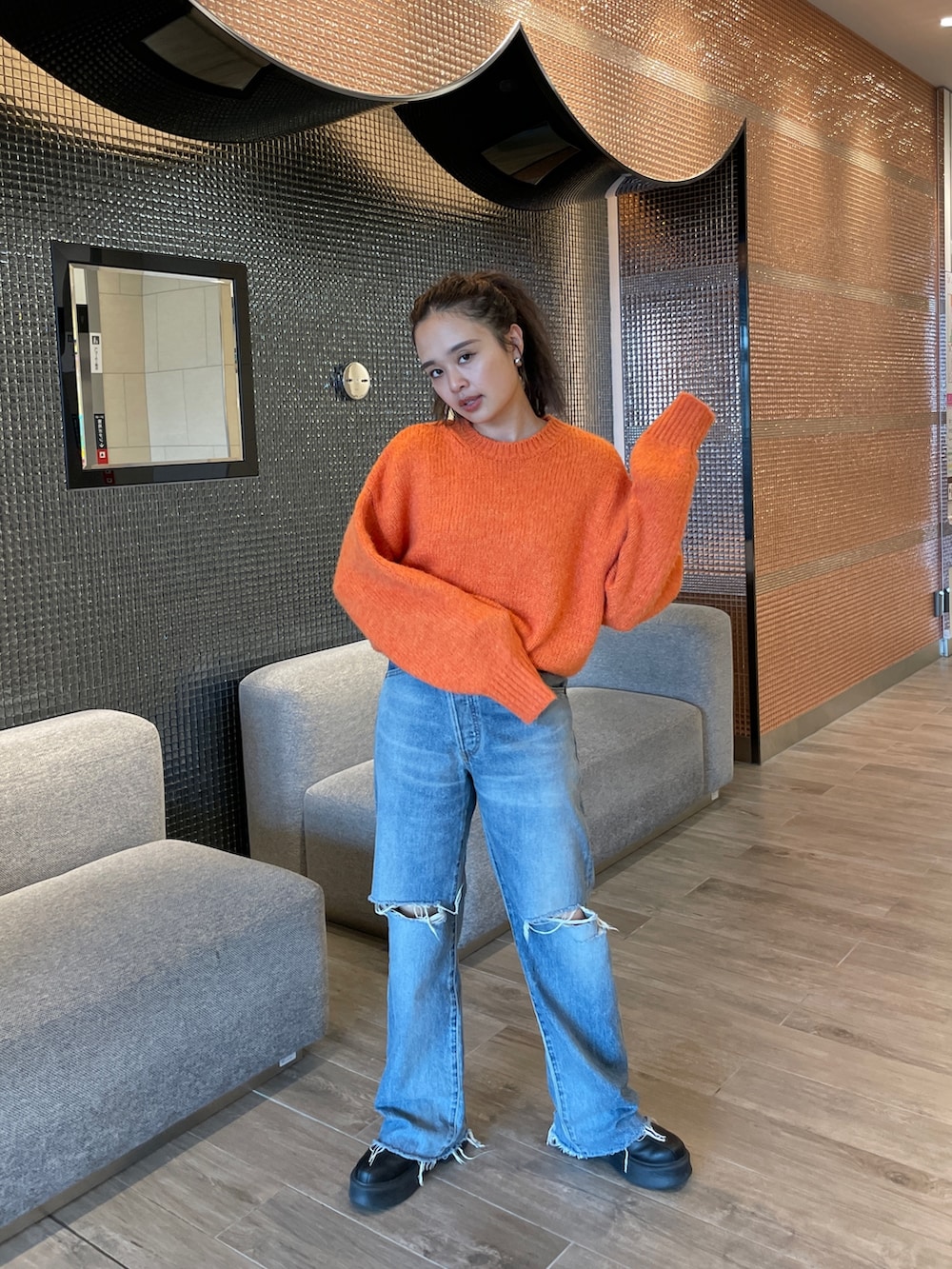 ブルー系のデニムパンツ、ブラック系のブーツ、オレンジ系のニット/セーターを着用したレディースの秋コーディネートの7枚目の写真