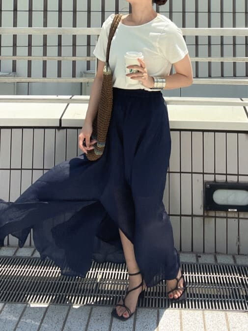 ブラウン系のトートバッグ、ホワイト系のTシャツ/カットソー、ブルー系のスカートを着用したレディースの春コーディネートの3枚目の写真
