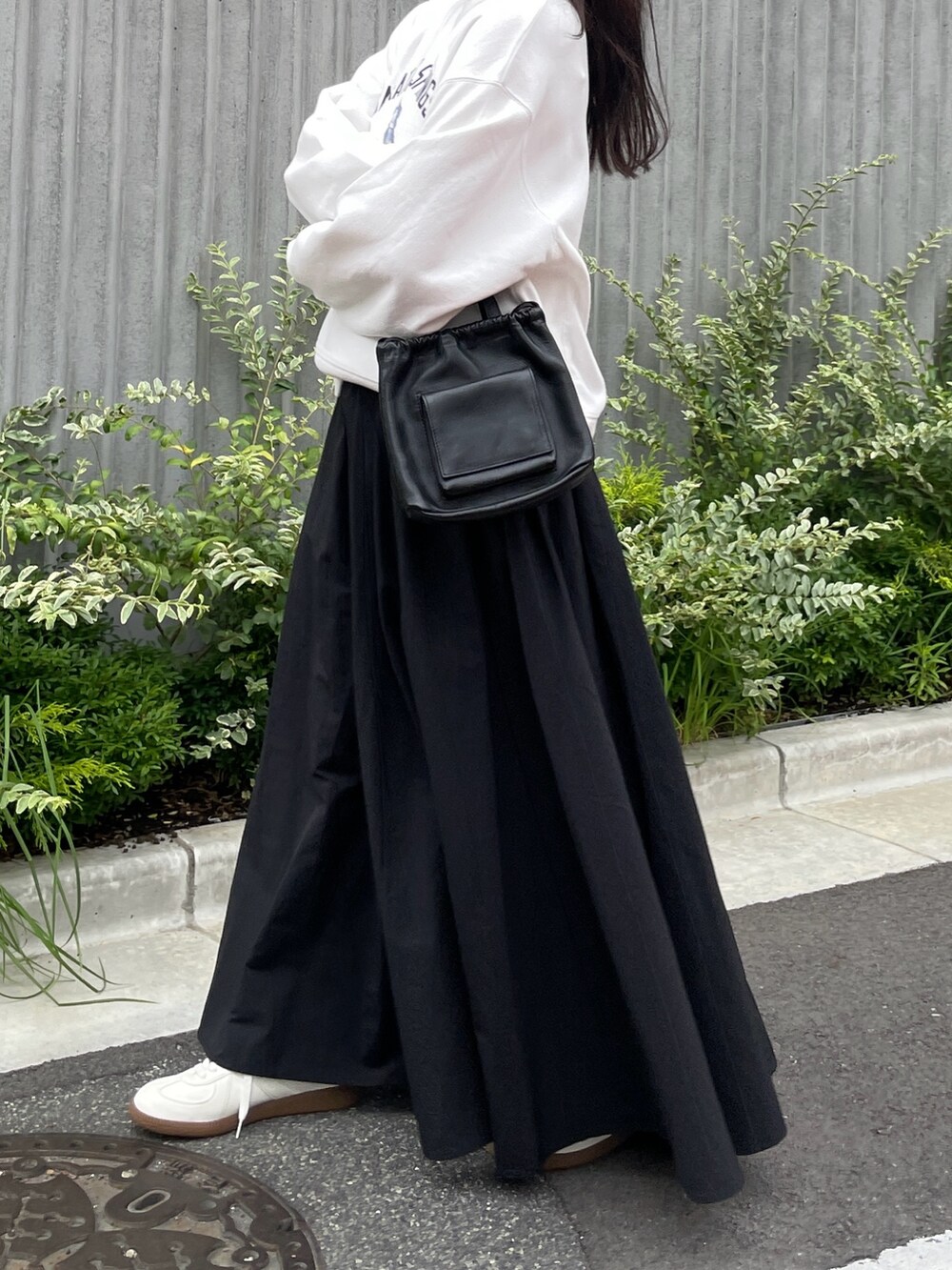 ホワイト系のスウェット、ブラック系のスカート、ブラック系のショルダーバッグを着用したレディースの夏コーディネートの3枚目の写真