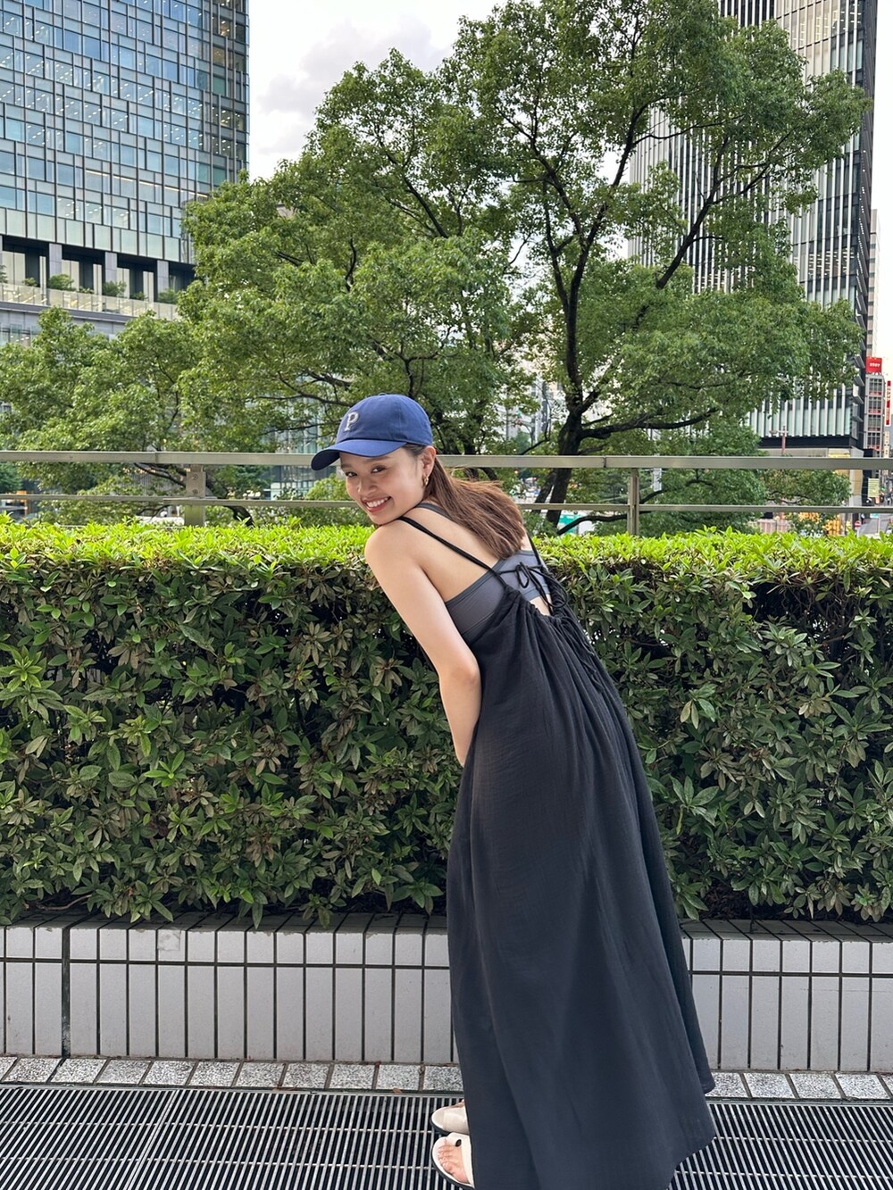 ブラック系のワンピース、ホワイト系のキャップを着用したレディースの夏コーディネートの2枚目の写真