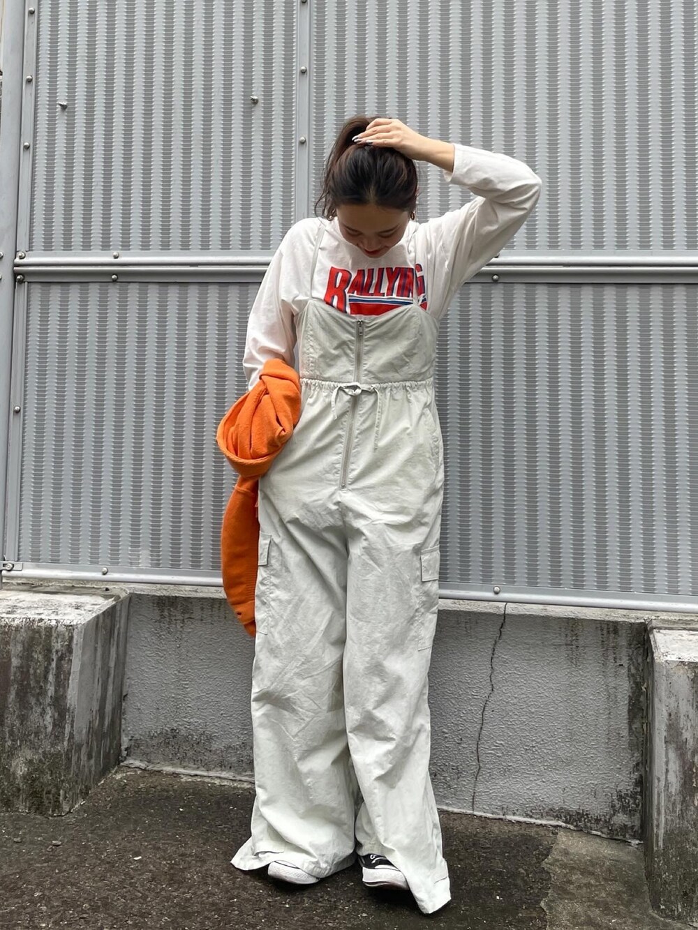 オレンジ系のカーディガン/ボレロ、ホワイト系のTシャツ/カットソー、グレー系のサロペット/オーバーオールを着用したレディースの冬コーディネートの4枚目の写真