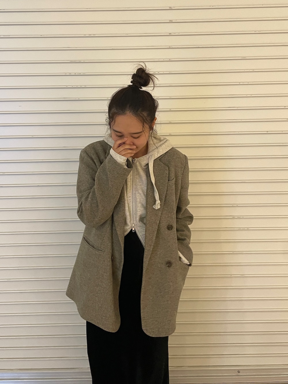 グレー系のテーラードジャケット、ホワイト系のパーカー、ブラック系のスカートを着用したレディースの秋コーディネートの2枚目の写真