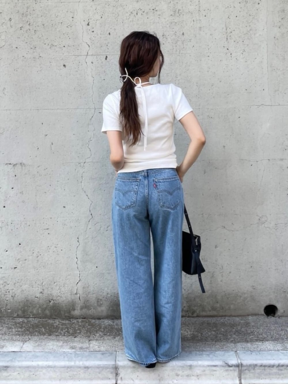 ブラック系のパンプス、ブルー系のデニムパンツ、ホワイト系のTシャツ/カットソーを着用したレディースの夏コーディネートの2枚目の写真