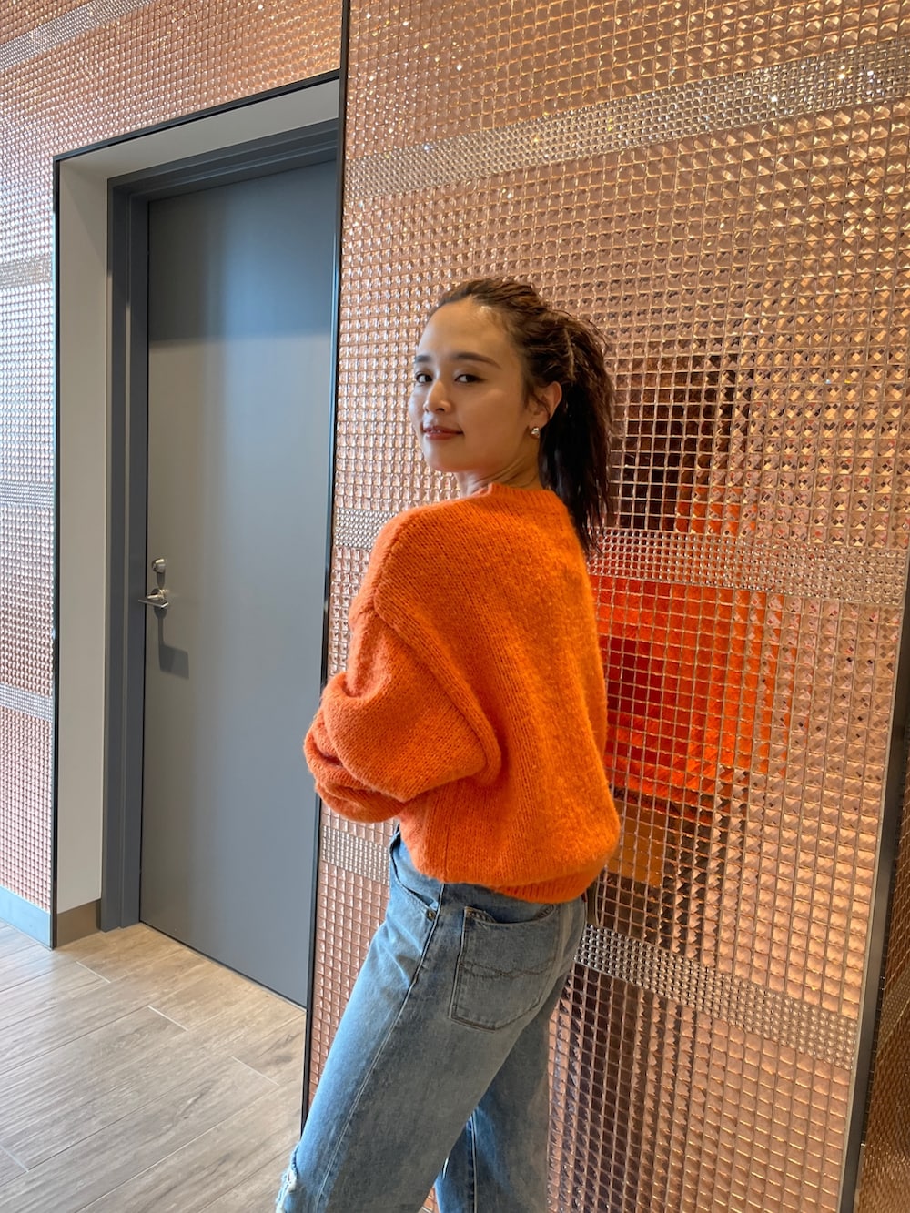 ブルー系のデニムパンツ、ブラック系のブーツ、オレンジ系のニット/セーターを着用したレディースの秋コーディネートの6枚目の写真