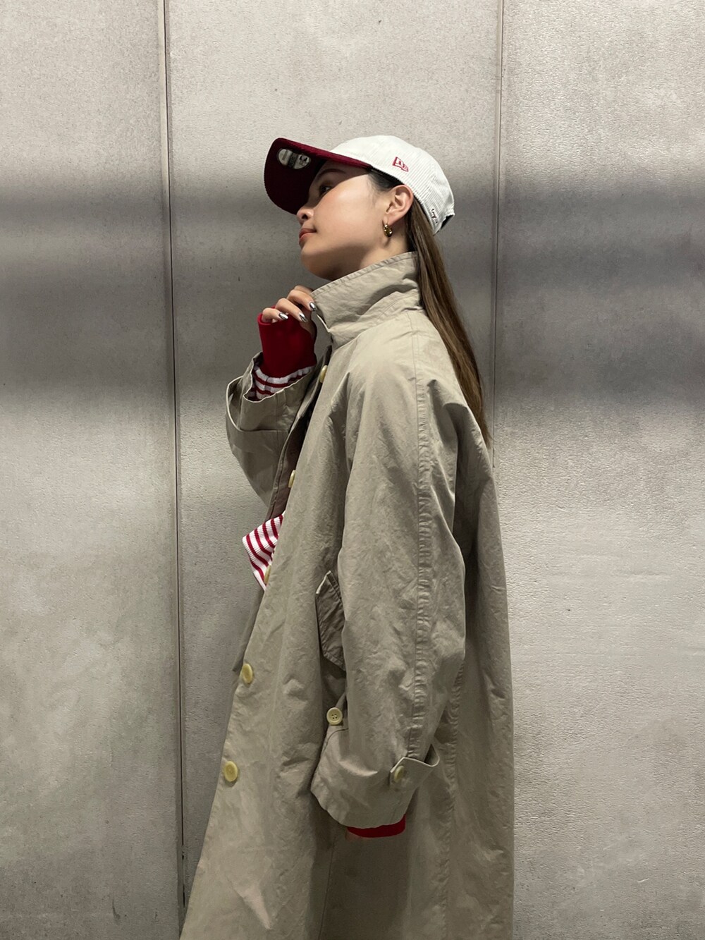 ブルー系のデニムパンツ、ベージュ系のステンカラーコート、レッド系のTシャツ/カットソーを着用したレディースの冬コーディネートの4枚目の写真