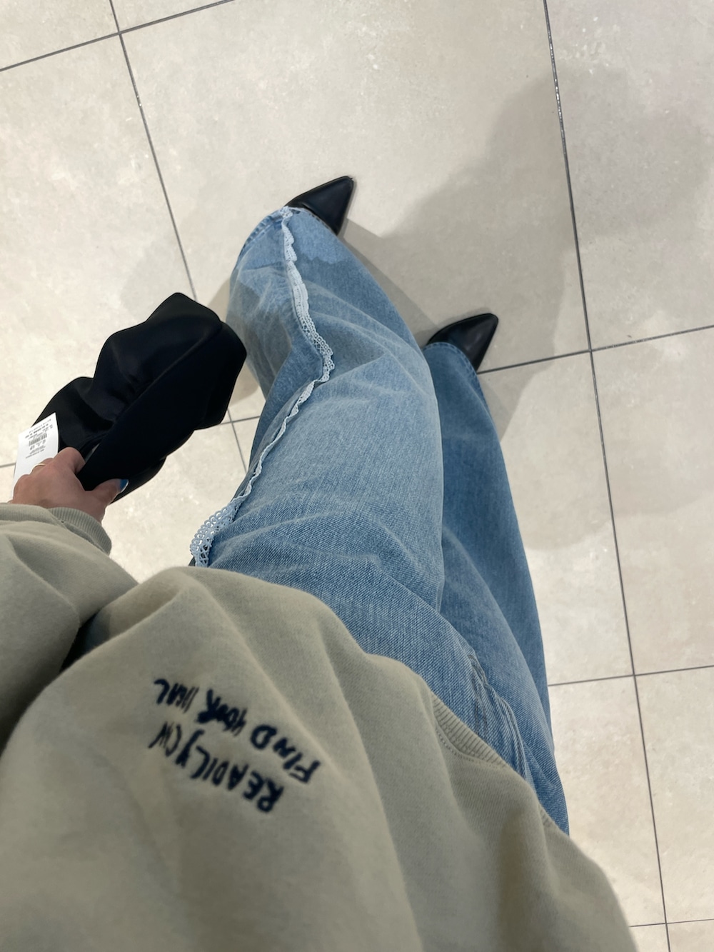 ベージュ系のスウェット、ブルー系のデニムパンツを着用したレディースの春コーディネートの4枚目の写真