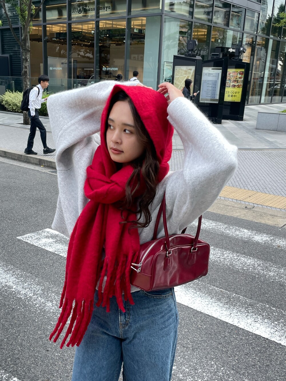 ブルー系のデニムパンツ、レッド系のハンドバッグ、グレー系のカーディガン/ボレロを着用したレディースの秋コーディネートの7枚目の写真