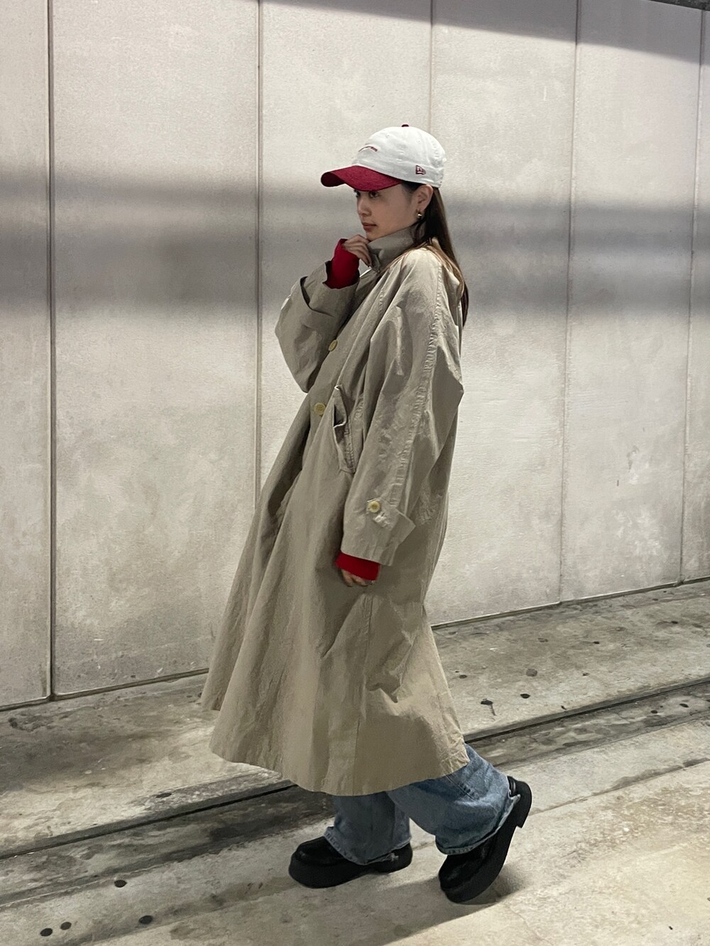 ブルー系のデニムパンツ、ベージュ系のステンカラーコート、レッド系のTシャツ/カットソーを着用したレディースの冬コーディネートの6枚目の写真