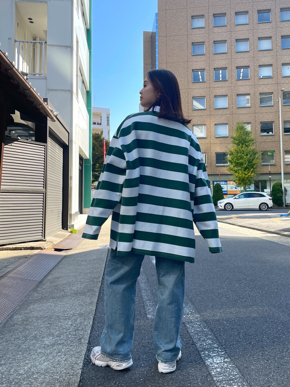グリーン系のTシャツ/カットソー、ブルー系のデニムパンツを着用したレディースの秋コーディネートの4枚目の写真