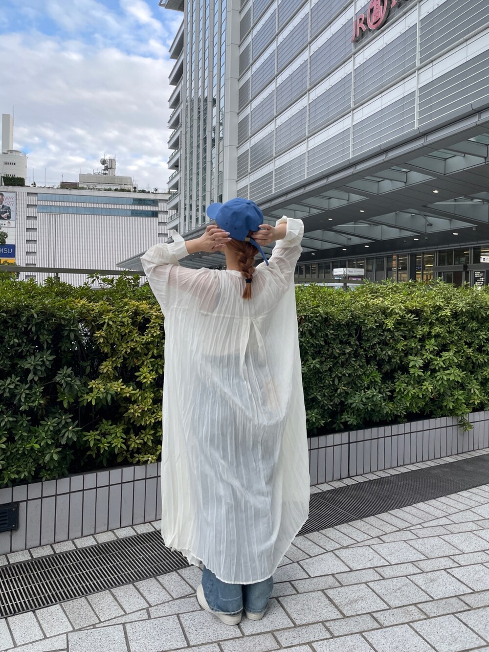 ブルー系のデニムパンツ、ホワイト系のスニーカー、ホワイト系のタンクトップを着用したレディースの春コーディネートの3枚目の写真