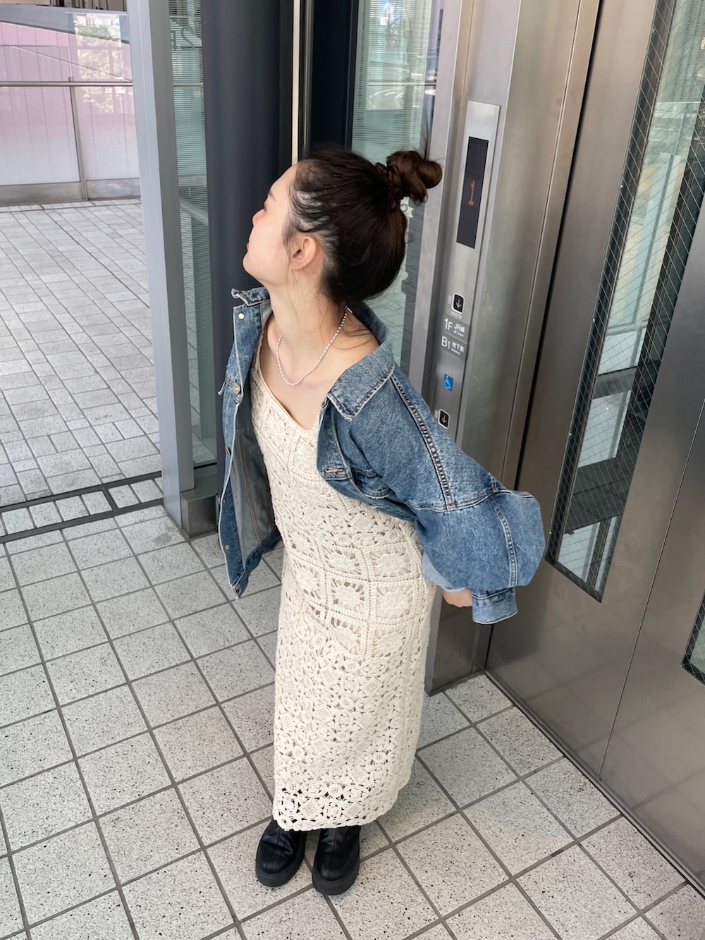 ブルー系のデニムジャケット、ベージュ系のワンピースを着用したレディースの春コーディネートの3枚目の写真