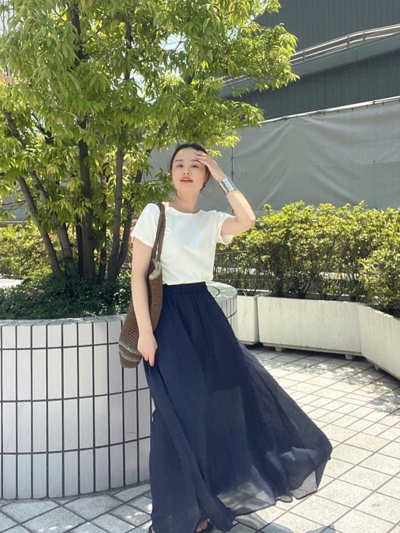 ブラウン系のトートバッグ、ホワイト系のTシャツ/カットソー、ブルー系のスカートを着用したレディースの春コーディネートの5枚目の写真