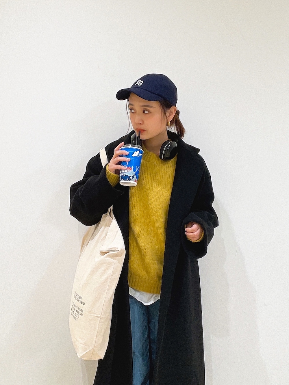 イエロー系のニット/セーター、ホワイト系のハンドバッグ、ブルー系のデニムパンツを着用したレディースの冬コーディネートの8枚目の写真