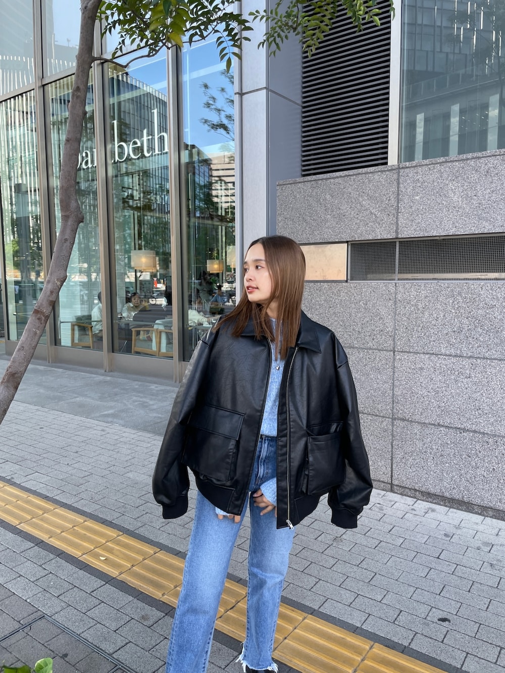 ブラック系のブルゾン、ブルー系のニット/セーター、ブルー系のデニムパンツを着用したレディースの秋コーディネートの6枚目の写真