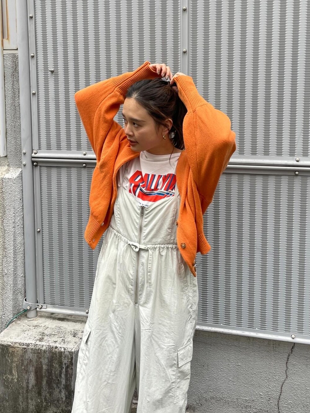 オレンジ系のカーディガン/ボレロ、ホワイト系のTシャツ/カットソー、グレー系のサロペット/オーバーオールを着用したレディースの冬コーディネートの2枚目の写真