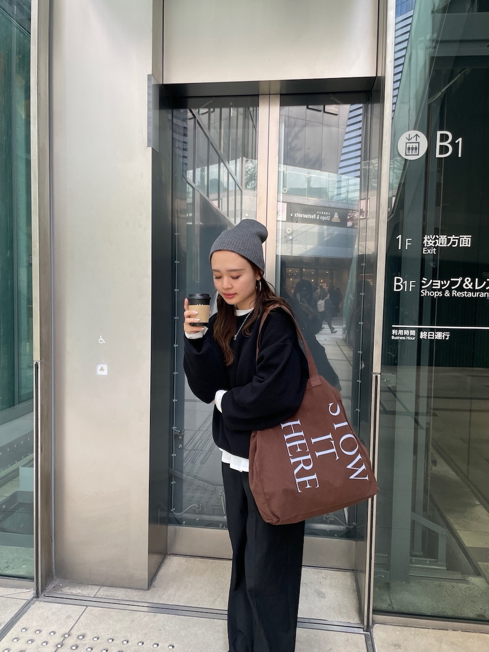 ブラック系のニット/セーター、ホワイト系のTシャツ/カットソー、ブラウン系のトートバッグを着用したレディースの冬コーディネートの2枚目の写真