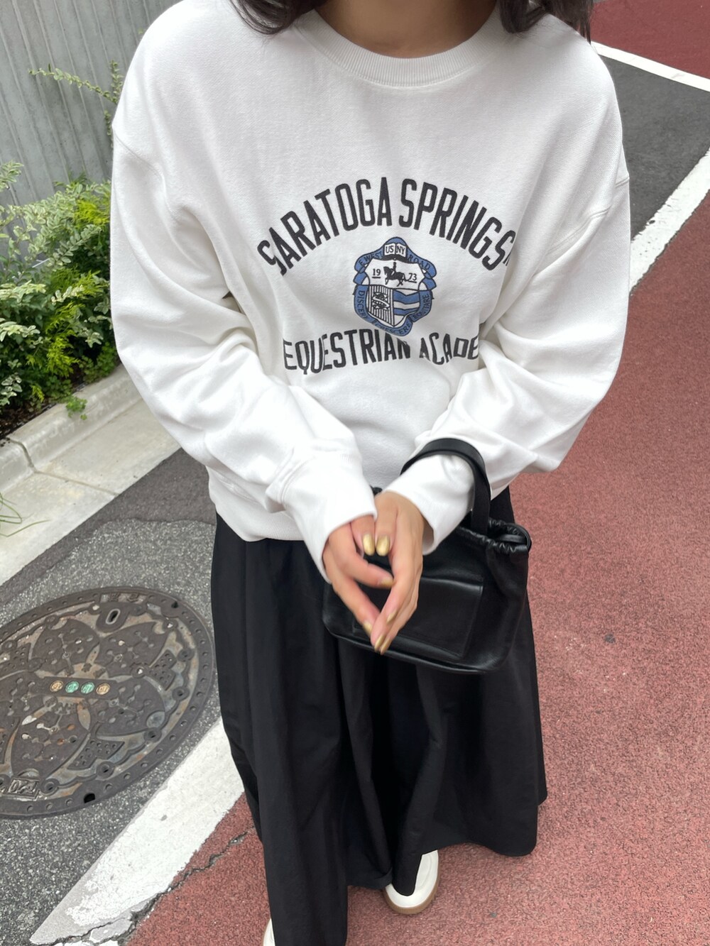 ホワイト系のスウェット、ブラック系のスカート、ブラック系のショルダーバッグを着用したレディースの夏コーディネートの2枚目の写真