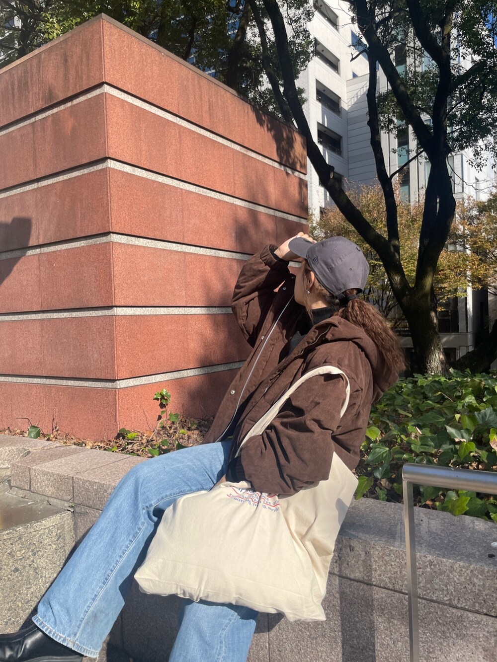 ブルー系のデニムパンツ、ブラウン系のブルゾン、ブラック系のニット/セーターを着用したレディースの冬コーディネートの2枚目の写真