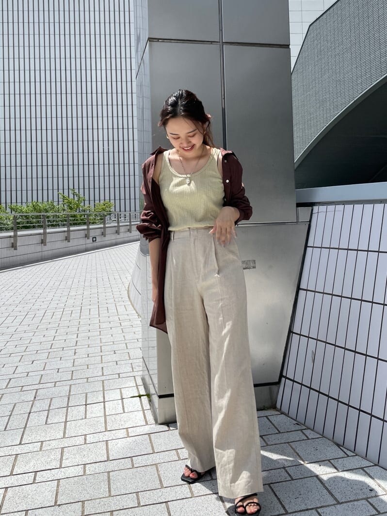 グリーン系のタンクトップ、ブラック系のサンダル、ホワイト系のその他パンツを着用したレディースの夏コーディネートの2枚目の写真